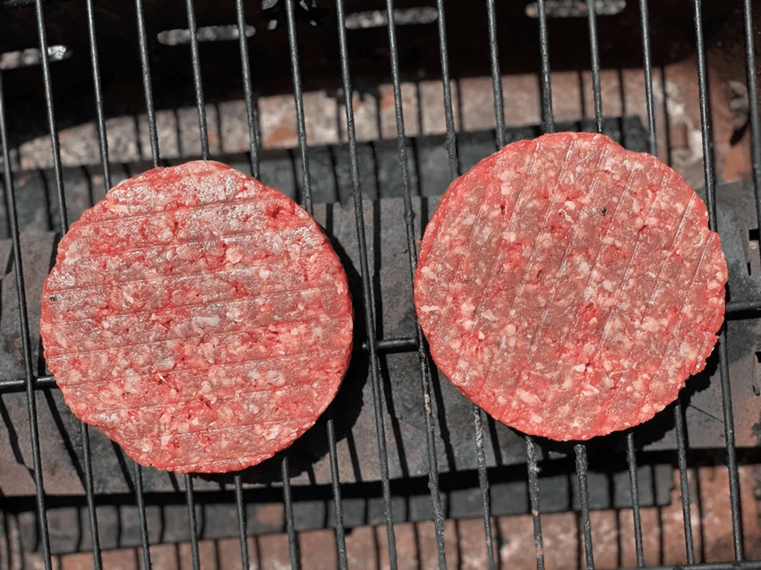 Two Hamburgers Sizzling on a Grill.