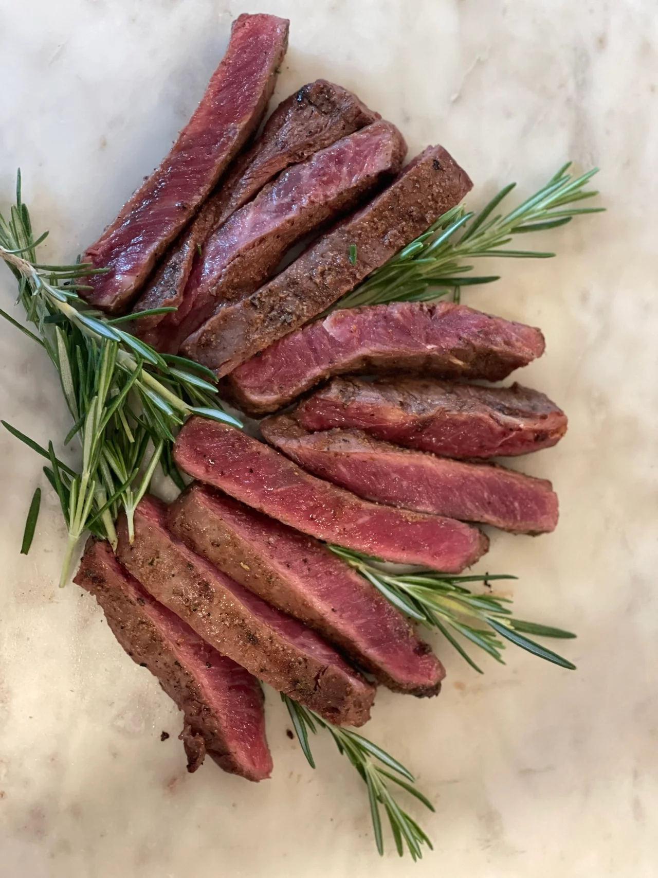 Sliced Beef With Rosemary on White Surface.