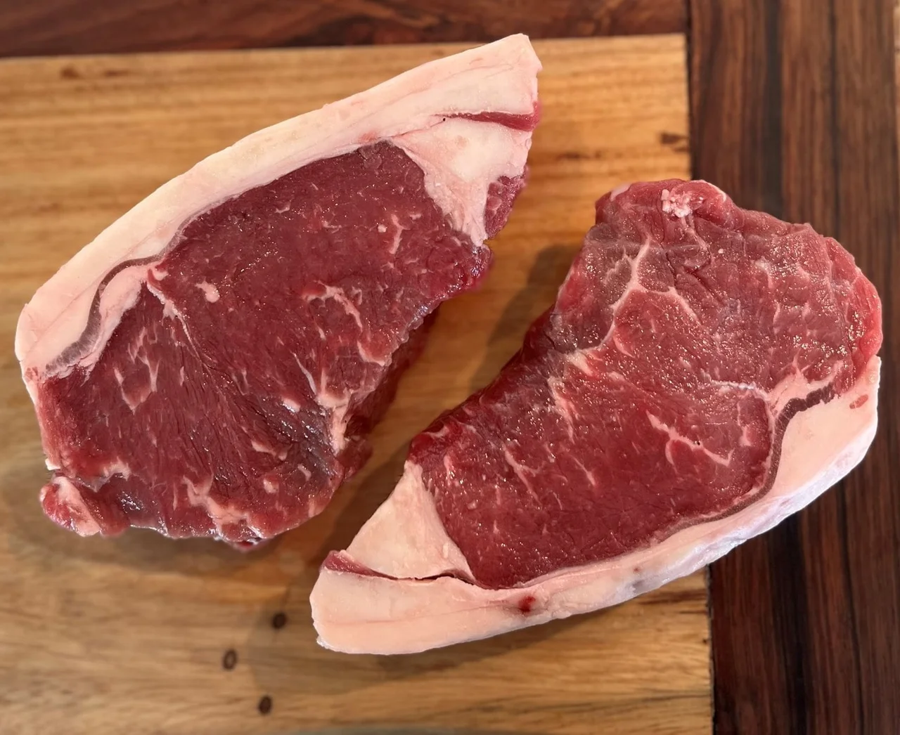 Two Juicy Steaks on a Wooden Cutting Board.
